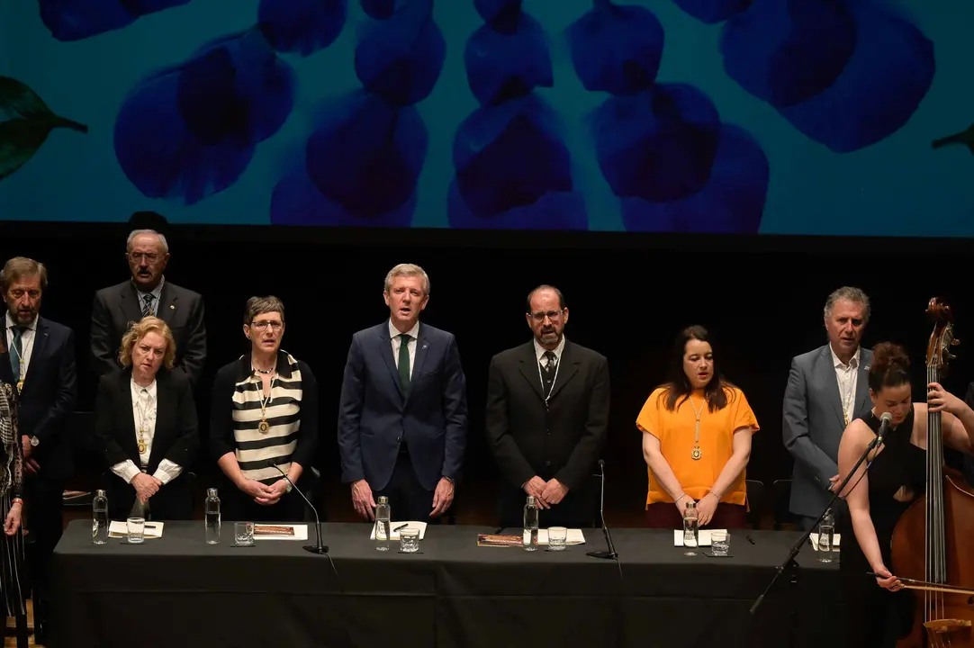 Representantes da Real Academia Galega e autoridades asistentes ao pleno extraordinario do D&iacute;a das Letras Galegas 2026, dedicado &aacute; escritora e xornalista Bego&ntilde;a Caama&ntilde;o, durante a celebraci&oacute;n no Teatro Principal de Santiago de Compostela.