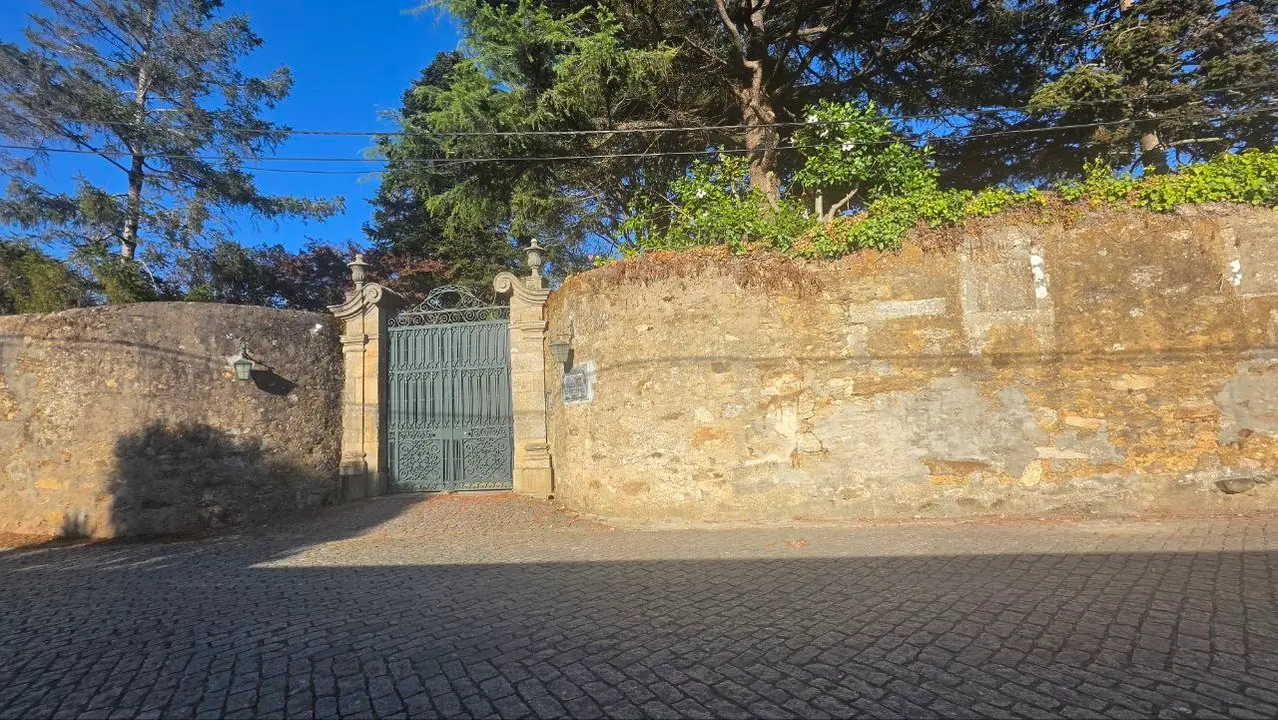 Uno de los accesos interiores de la propiedad, abierto entre pilares de piedra y rodeado por el arbolado que caracteriza el recinto de Enxomil.