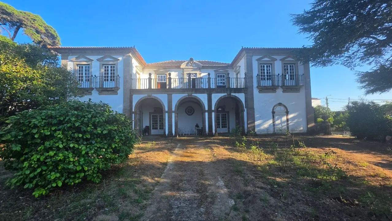 Vista frontal de uno de los principales cuerpos residenciales de la Quinta de Enxomil, articulado mediante una galer&iacute;a de tres arcos, balcones de hierro y recercados de granito.