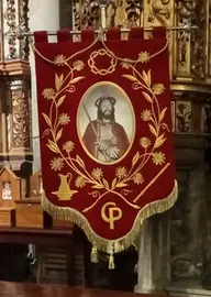 Estandarte de la Hermandad del Cristo Resucitado para la procesi&oacute;n de la Santa Cena, con fondo rojo y simbolog&iacute;a de la Pasi&oacute;n como la corona de espinas y la ca&ntilde;a del Ecce Homo.