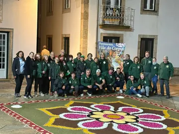 Integrantes de la Asociaci&oacute;n de Alfombristas do Corpus Christi de Ponteareas junto a la alfombra floral que simboliza el hermanamiento cultural entre Galicia y Portugal.