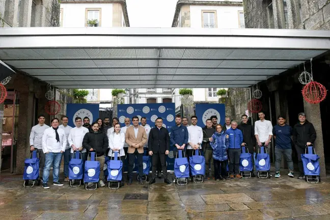Autoridades, vendedores y chefs, en grupo y con sus carritos de la compra, a las puertas de la Plaza de Abastos de Santiago en el acto de presentación de Plato de Mercado.

Si quieres, puedo hacerla más breve, más formal o con nombres concret