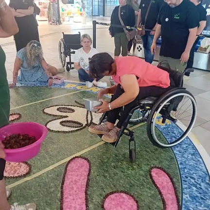 Participantes elaborando una alfombra inclusiva, mostrando cómo el Corpus de Ponteareas integra a personas con diferentes capacidades en la tradición.