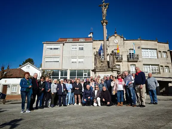 El grupo de 55 vecinos de Nigr&aacute;n posa junto al cruceiro de Covelo durante su visita cultural al municipio pontevedr&eacute;s.