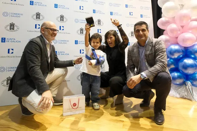 Un ni&ntilde;o celebra su premio junto a representantes institucionales durante el acto celebrado en Santiago de Compostela.