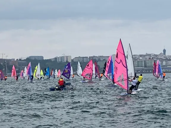 La flota de windsurfers, con velas multicolor, durante una de las mangas disputadas en la bah&iacute;a coru&ntilde;esa, en una jornada marcada por el viento variable y el mal tiempo.