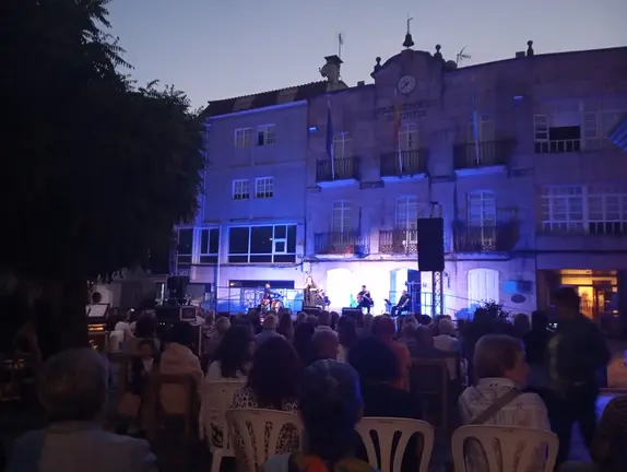 O p&uacute;blico enche a Praza do Mestre Cervi&ntilde;o para asistir ao concerto de Mar&iacute;a do Ceo, coa Casa do Concello de Covelo como pano de fondo.