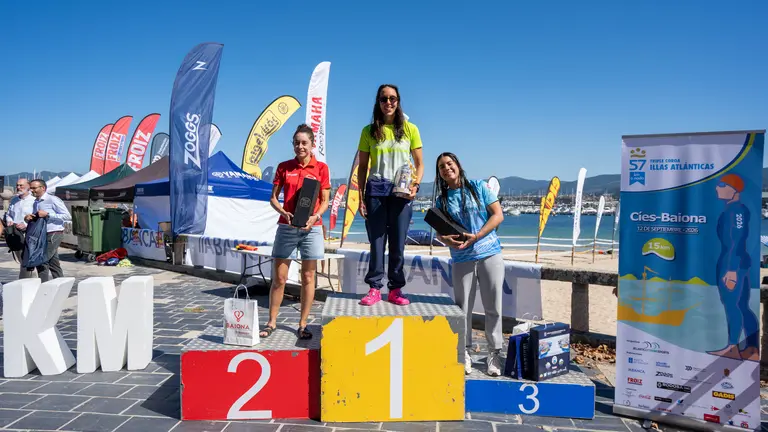 Podio femenino de la C&iacute;es-Baiona: Sheila S&aacute;nchez Castillo, en el centro, celebra la victoria en la categor&iacute;a absoluta femenina, acompa&ntilde;ada por las otras dos integrantes del podio, tras completar una de las pruebas m&aacute;s exigentes de nataci&oacute;n en aguas abiertas.