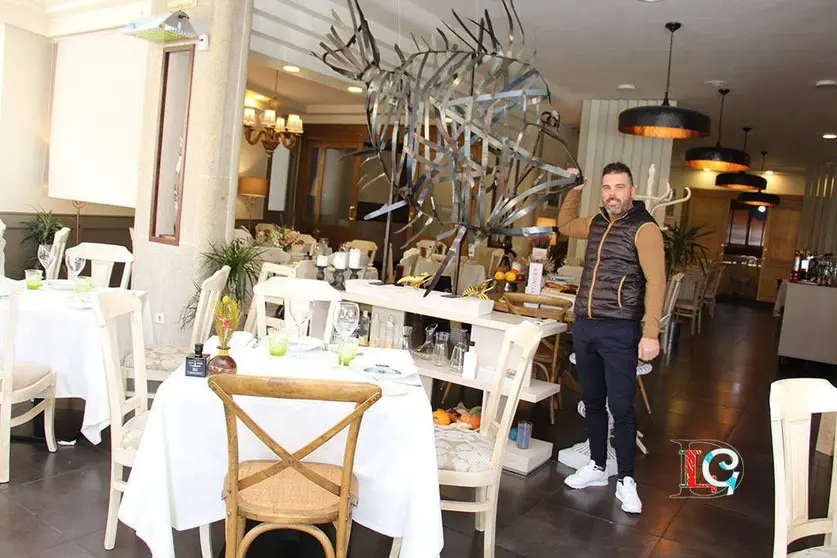 Carlos Fernández, en el comedor de O Barazal, junto a la escultura de un pez de San Pedro. 