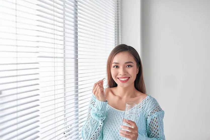Una chica toma aceite de pescado, mediante un complemento alimenticios con omega 3 que disminuyen el déficit de ácidos grasos en la ingesta diaria de alimentos.