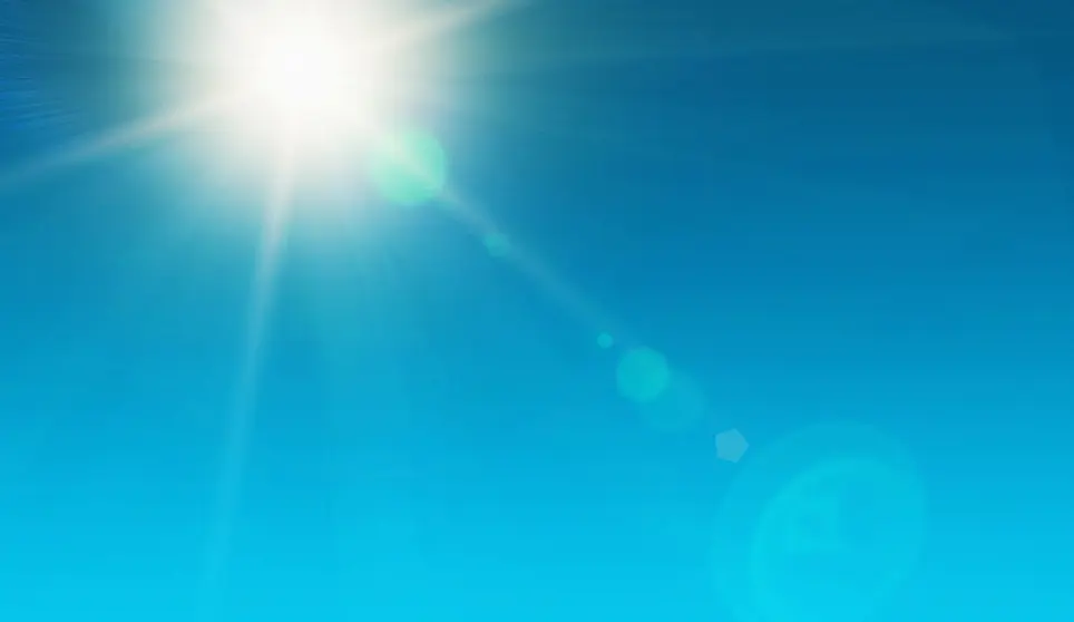 Looking up at the dazzling sun, high in the noonday sky and showing natural zoom lens flare. The source of our solar power. Ample copy space on sky.