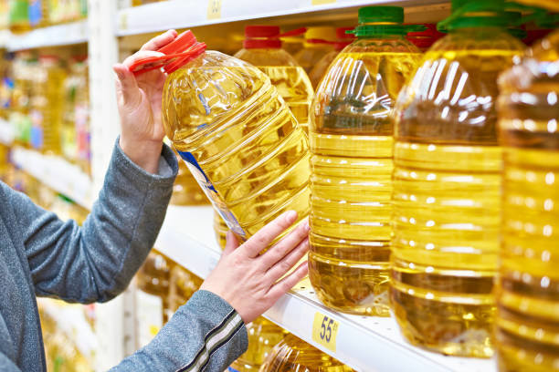 Gran botella de plástico de aceite de oliva en la mano del comprador en el supermercado.