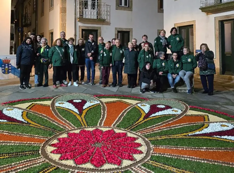 El equipo de alfombristas de Ponteareas y Monção, incluyendo niños y celebrando el 89 cumpleaños de Elvira, posan orgullosos junto a su creación floral.