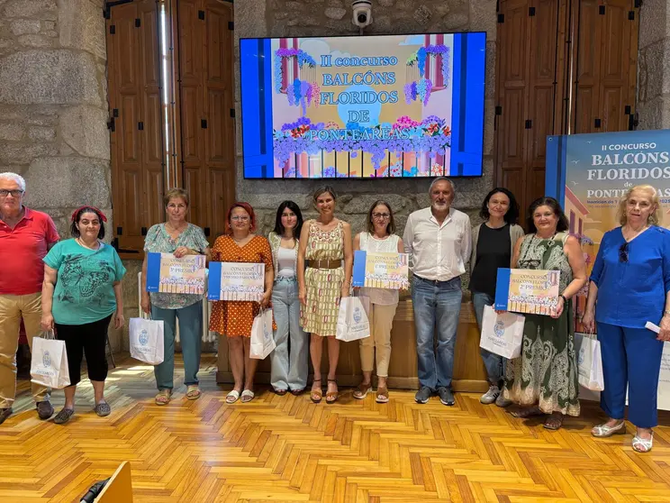 Los vecinos galardonados en el concurso "Balcóns Floridos" de Ponteareas posan con sus premios, celebrando la belleza y sostenibilidad que aportan a la villa.