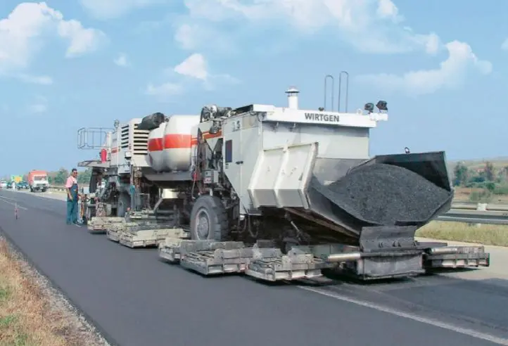 Un camión de asfaltado trabaja en la rehabilitación de una carretera, parte del plan del Ministerio de Transportes para renovar 114 km de la Red de Carreteras del Estado con materiales sostenibles.