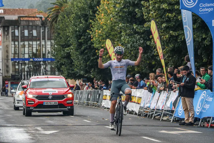 El valenciano Enrique Maranchón (Picusa Academy) levanta los brazos en la meta de Noia, culminando una exhibición en solitario que le dio la victoria en el III Trofeo Portus Apostoli y el premio de la Montaña.