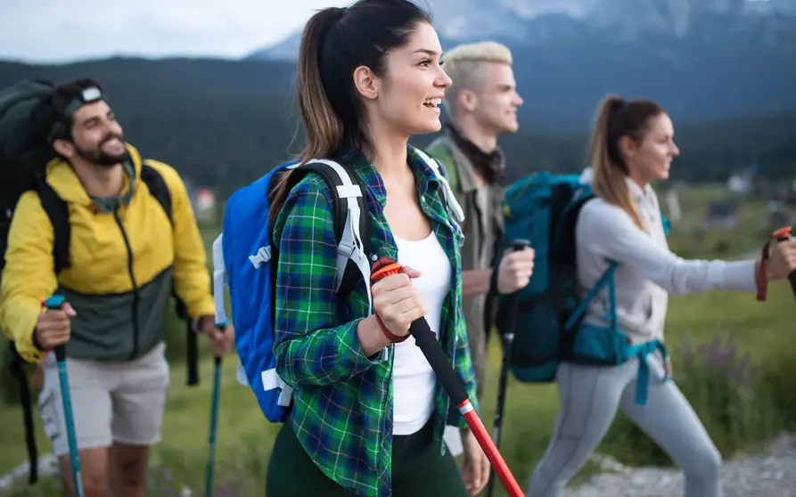 Concepto de aventura, viajes, turismo, caminatas y personas: un grupo de amigos sonrientes haciendo senderismo.