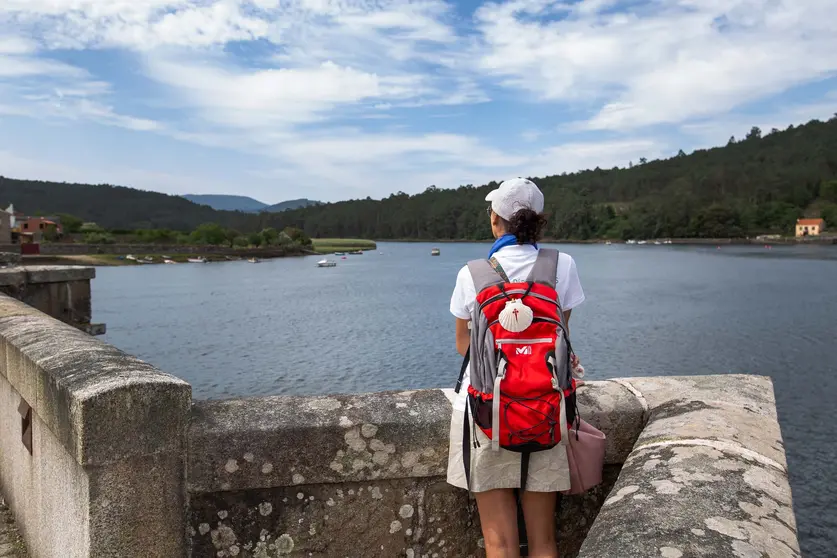 Una peregrina contempla la ría de Muros Noia desde lo alto del Camino, una de las rutas más singulares hacia Santiago de Compostela.