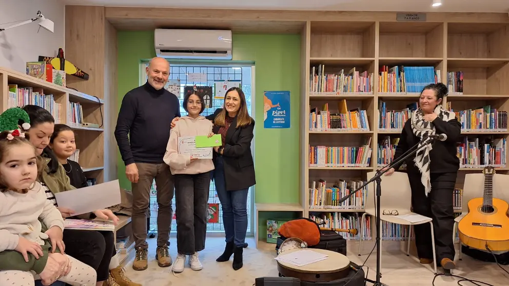 El teniente de alcalde, Camilo Grandal, y la concejala de Cultura, Sara Cebreiro, junto a una de las premiadas del Concurso de Postales de Navidad en la Biblioteca Municipal Mar&iacute;a Magdalena de Mos.