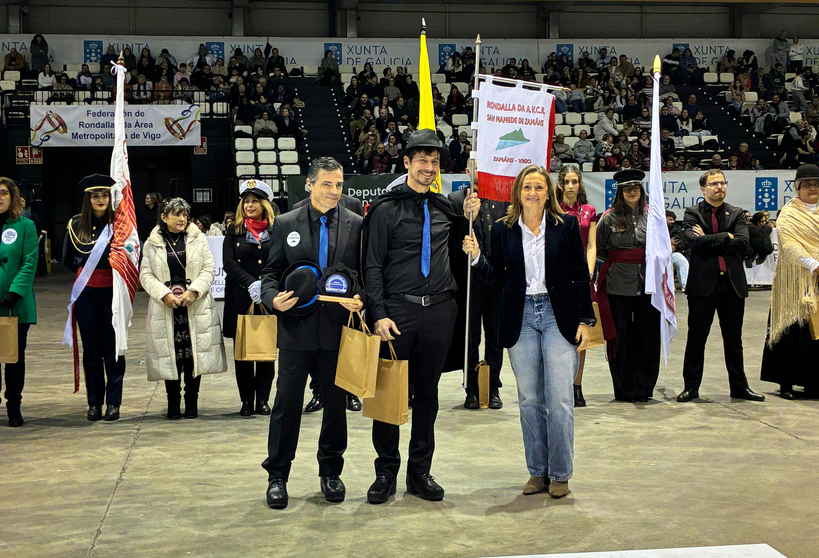 Entrega de reconocimientos durante el VIII Concurso de Rondallas del &Aacute;rea Metropolitana de Vigo, con representantes institucionales y miembros de una de las agrupaciones participantes en el centro del recinto.