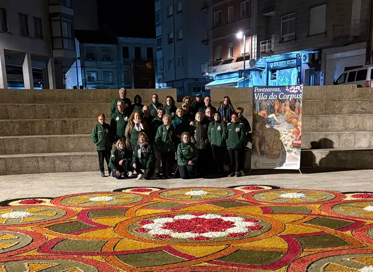 Integrantes de la Asociaci&oacute;n de Alfombristas do Corpus Christi de Ponteareas posan junto a la alfombra floral realizada en la Plaza de San Ram&oacute;n, en O Carballi&ntilde;o.