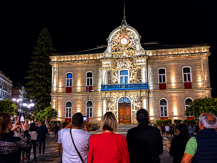 Vecinos y visitantes siguen la proyecci&oacute;n art&iacute;stica sobre el hist&oacute;rico edificio consistorial de Ponteareas durante una concurrida velada nocturna. A. OUTERELO.
