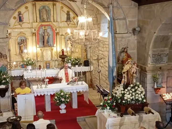 Interior da igrexa de Santa Mar&iacute;a de Para&ntilde;os durante unha celebraci&oacute;n relixiosa, co altar maior ao fondo e a imaxe da Virxe do Carme engalanada para a procesi&oacute;n, unha das devoci&oacute;ns con maior arraigamento na parroquia.