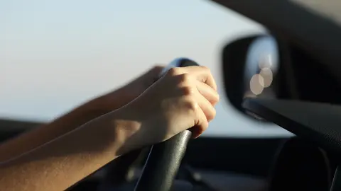 Driver hands holding steering wheel driving a car