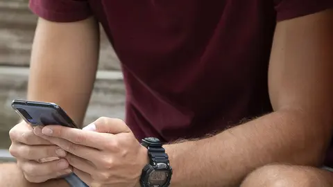 Un mozo navega co seu teléfono móvil.