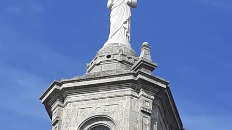 La imagen en perfecta consonancia con el volumen y estética de la torre que la sostiene, pesa 10 toneladas y tiene 6 metros de altura.