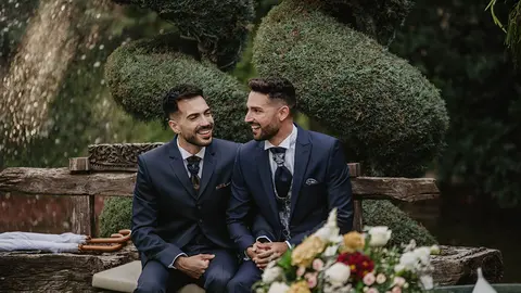 El clásico traje azul oscuro con corbata o pajarita sigue siendo el preferido para los novios, que añaden algún complemento con el que aportar personalidad y carácter al look (Fotografía de Mía Moments Photo vía Bodas.net).