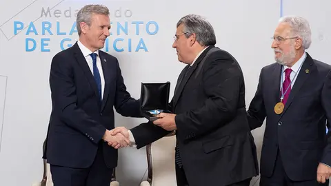 António Cunha, presidente da Eurorrexión, recibe de mans do presidente da Xunta, Alfonso Rueda, e acompañado polo presidente do Parlamento galego, Miguel Santalices, a medalla.