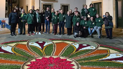 El equipo de alfombristas de Ponteareas y Monção, incluyendo niños y celebrando el 89 cumpleaños de Elvira, posan orgullosos junto a su creación floral.