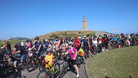 El pelotón de ciclistas colorea el paseo marítimo, con la majestuosa Torre de Hércules como telón de fondo. ¡A Coruña en estado puro!
