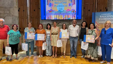 Los vecinos galardonados en el concurso "Balcóns Floridos" de Ponteareas posan con sus premios, celebrando la belleza y sostenibilidad que aportan a la villa.