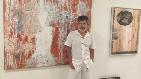 El artista Colin Baldwin junto a una de las obras de su serie "Línea Bruta", una exposición que reflexiona sobre la agitación interna en la era digital.