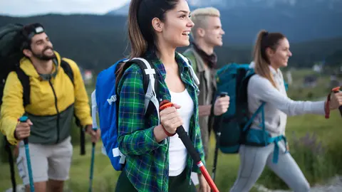 Concepto de aventura, viajes, turismo, caminatas y personas: un grupo de amigos sonrientes haciendo senderismo.