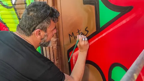 O artista arcuense MUTES em plena criação do seu primeiro mural internacional no Canadá, transformando a Rua Brock numa explosão de cores e formas.