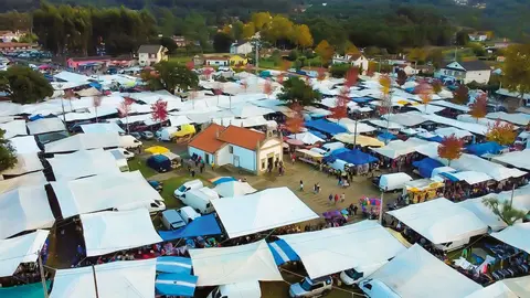 Vista cenital de la Feria de los Santos de Cerdal, con los coloridos puestos rodeando la capilla de San Antonio, epicentro de esta cita tradicional en Valença.