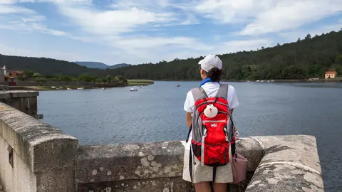 Una peregrina contempla la ría de Muros Noia desde lo alto del Camino, una de las rutas más singulares hacia Santiago de Compostela.
