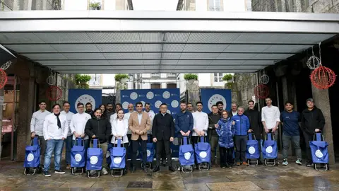 Autoridades, vendedores y chefs, en grupo y con sus carritos de la compra, a las puertas de la Plaza de Abastos de Santiago en el acto de presentación de Plato de Mercado.

Si quieres, puedo hacerla más breve, más formal o con nombres concret