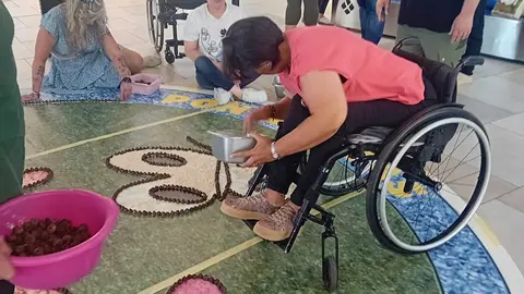 Participantes elaborando una alfombra inclusiva, mostrando cómo el Corpus de Ponteareas integra a personas con diferentes capacidades en la tradición.