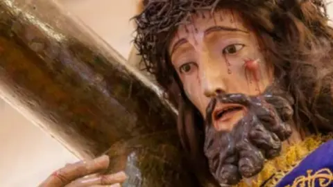 Imagen de la portada del &ldquo;Libro de Irm&aacute;ns&rdquo; 2026, con una talla de Cristo cargando la cruz, una de las escenas m&aacute;s representativas de la Semana Santa de Cangas.