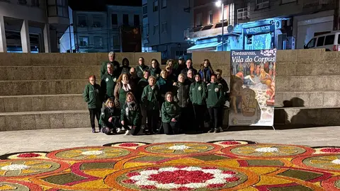 Integrantes de la Asociaci&oacute;n de Alfombristas do Corpus Christi de Ponteareas posan junto a la alfombra floral realizada en la Plaza de San Ram&oacute;n, en O Carballi&ntilde;o.