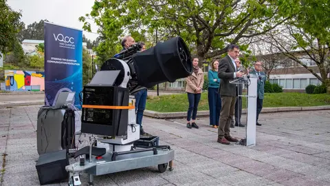 El conselleiro Rom&aacute;n Rodr&iacute;guez interviene durante la inauguraci&oacute;n de la infraestructura, junto al equipo investigador, con el sistema &oacute;ptico preparado para comunicaciones cu&aacute;nticas en primer plano.