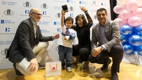 Un ni&ntilde;o celebra su premio junto a representantes institucionales durante el acto celebrado en Santiago de Compostela.