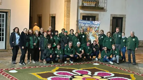 Integrantes de la Asociaci&oacute;n de Alfombristas do Corpus Christi de Ponteareas junto a la alfombra floral que simboliza el hermanamiento cultural entre Galicia y Portugal.