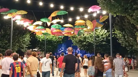 Ambiente festivo en Mondariz durante as festas de San Roque e da Virxe da Pe&ntilde;a de Francia, con veci&ntilde;os e visitantes gozando da m&uacute;sica e da iluminaci&oacute;n ornamental na vila.