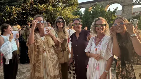 Varias asistentes contemplan el eclipse con gafas especiales de protecci&oacute;n durante la celebraci&oacute;n solidaria.