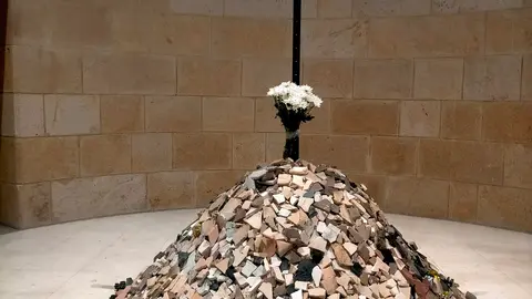 O milladoiro da memoria. Un c&uacute;mulo de pedras coroado por flores ocupa o antigo pan&oacute;ptico do MARCO na exposici&oacute;n Hai un lugar, de Alberto Ardi, como s&iacute;mbolo do punto onde unha vida quedou truncada e, ao mesmo tempo, como ofrenda colectiva &aacute; memoria das v&iacute;timas.